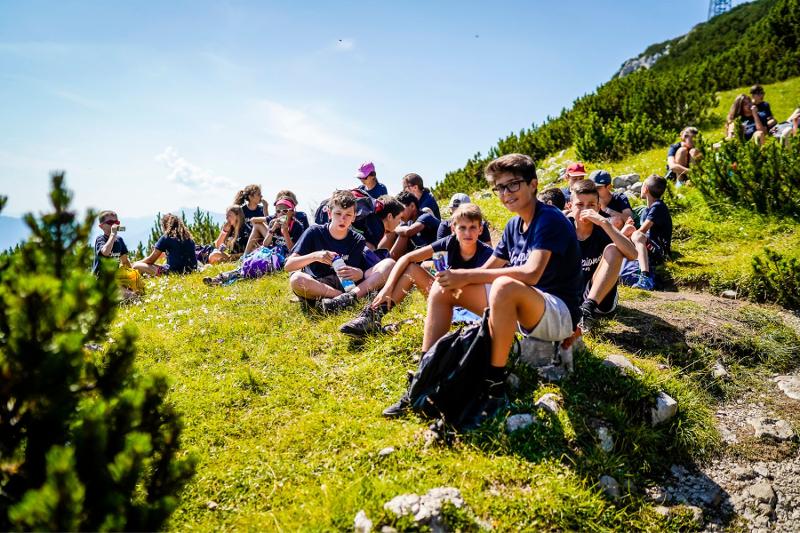 Un gruppo di partecipanti del campo estivo tecniche di memoria mangia il proprio pranzo seduto su di un prato di montagna