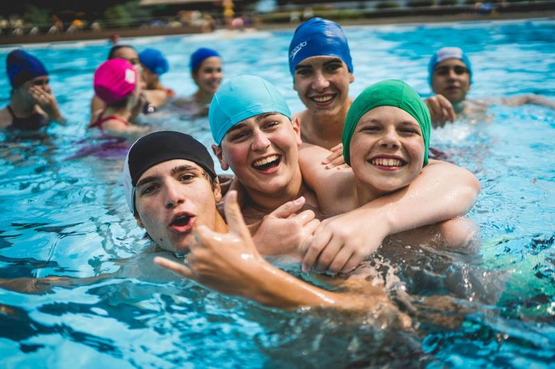 Un gruppo di ragazzi del campo estivo tecniche di memoria si abbraccia scherzosamente in piscina