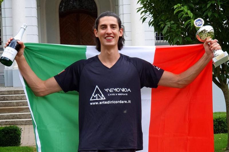 Un ragazzo del campo estivo tecniche di memoria festeggia la sua vittoria con una bandiera tricolore, la coppa e una bottiglia di champagne