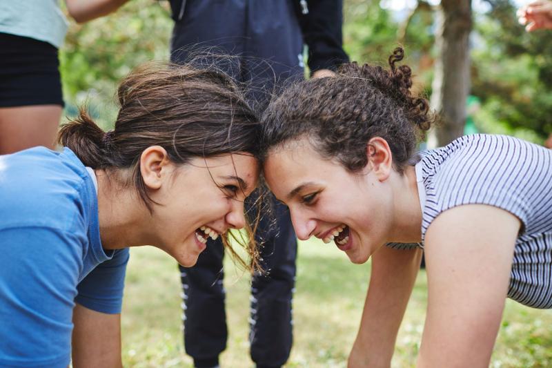Due ragazze del campo estivo musical ridono testa a testa durante un'attività