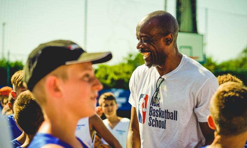 Un allenatore del campo estivo NBA ride e scherza con dei giovani giocatori