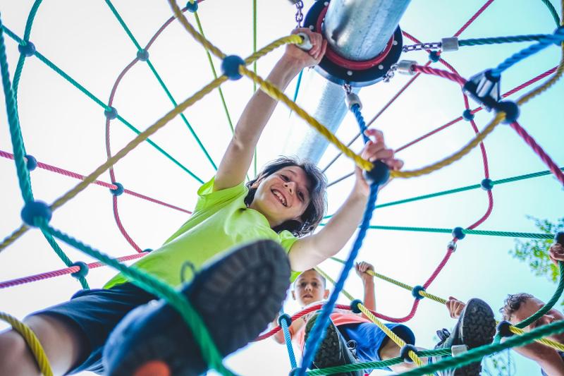 I partecipanti del campo estivo Padel si arrampicano su una struttura di un parco giochi