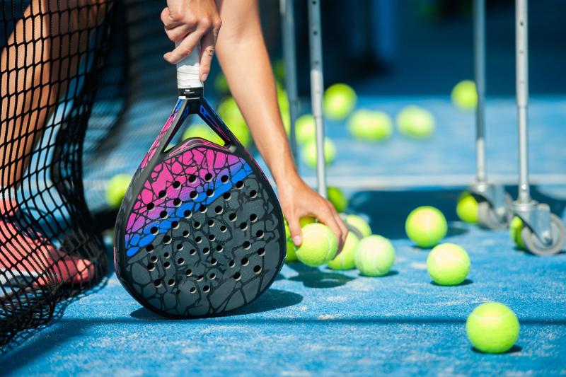 Un partecipante del campo estivo Padel raccogli le palline dall'altro lato della rete