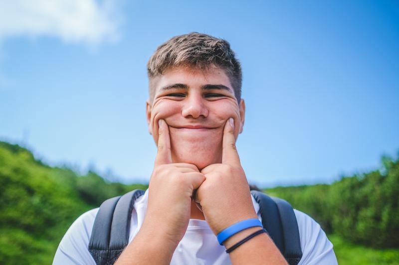 Un ragazzo del campo estivo Padel finge un sorriso in modo scherzoso facendosi pressione sulle guance