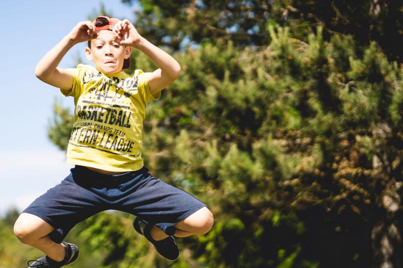 Un ragazzo esegue un lungo e alto salto al campo estivo Parkour