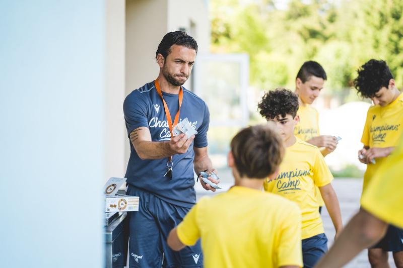 Un allenatore del campo estivo calcio dà delle merendine ai partecipanti