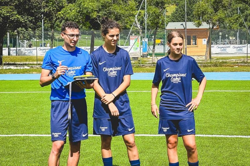Tre ragazzi del campo estivo calcio eseguono un'analisi della partita davanti agli altri partecipanti