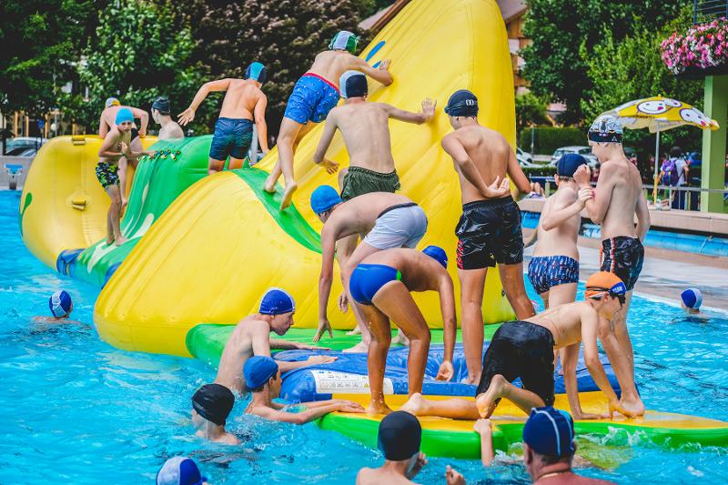 Un gruppo di ragazzi del campo estivo calcio si diverte sui giochi gonfiabili in piscina