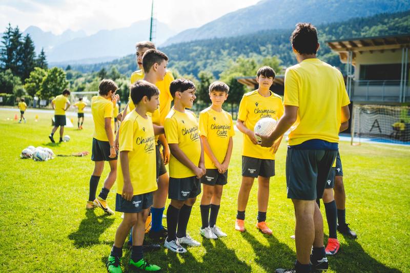 Un gruppo di ragazzi del campo estivo calcio ascolta le istruzioni dei coach in campo