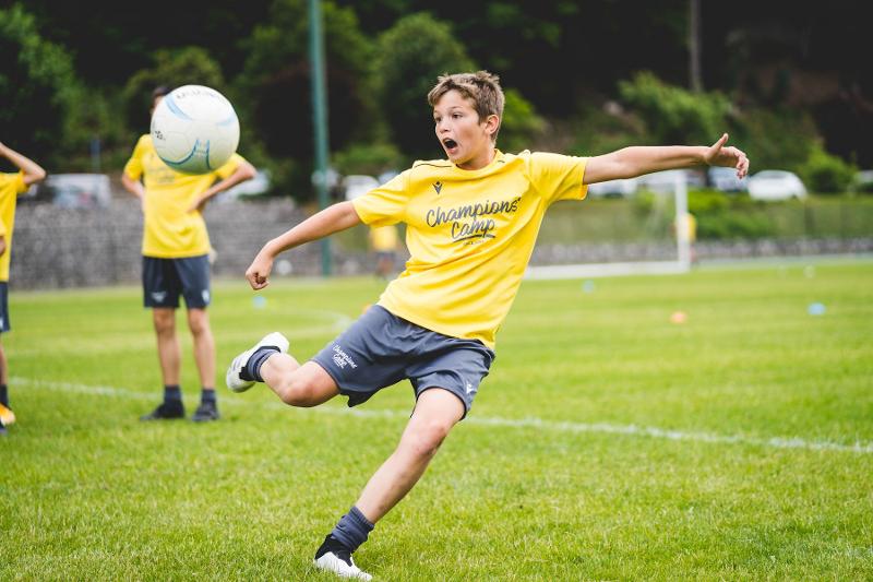 Un partecipante del campo estivo calcio si appresta a eseguire un tiro al volo