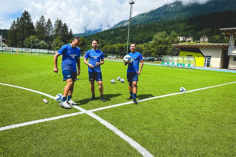 I tre allenatori del campo estivo calcio raccolgono le palle a centro campo