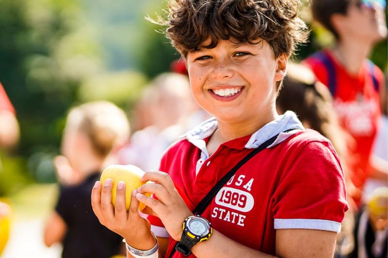 Un ragazzo mangia una mela al campo estivo inglese e sport