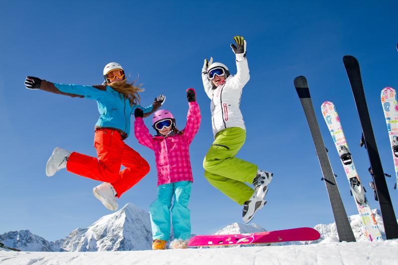 Tre ragazze in cima lla montagna saltano al campo invernale sci e snowboard
