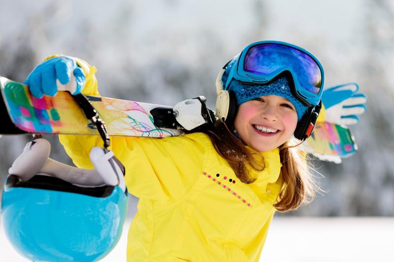 Una ragazza si carica gli sci in spalla al campo invernale sci e snowboard