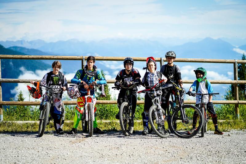 Un gruppo di partecipanti del campo estivo mountain bike si siede sulle rispettive biciclette e fa una foto di gruppo 