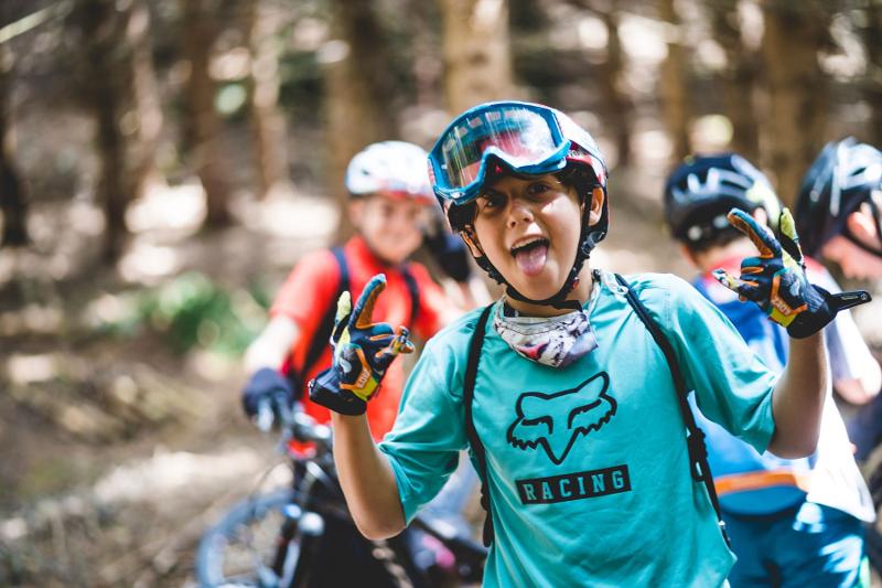 Un ragazzo fa pose divertenti durante un'uscita in bicicletta al campo estivo mountain bike