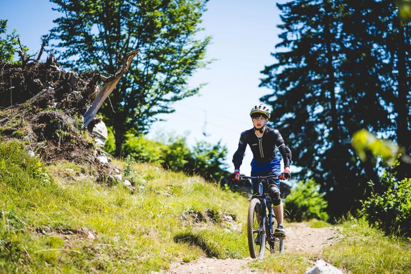 Un ragazzo pedala lungo un sentiero scosceso al campo estivo mountain bike