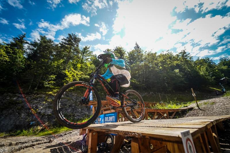 Un partecipante del campo estivo mountain bike si appresta ad eseguire un salto 