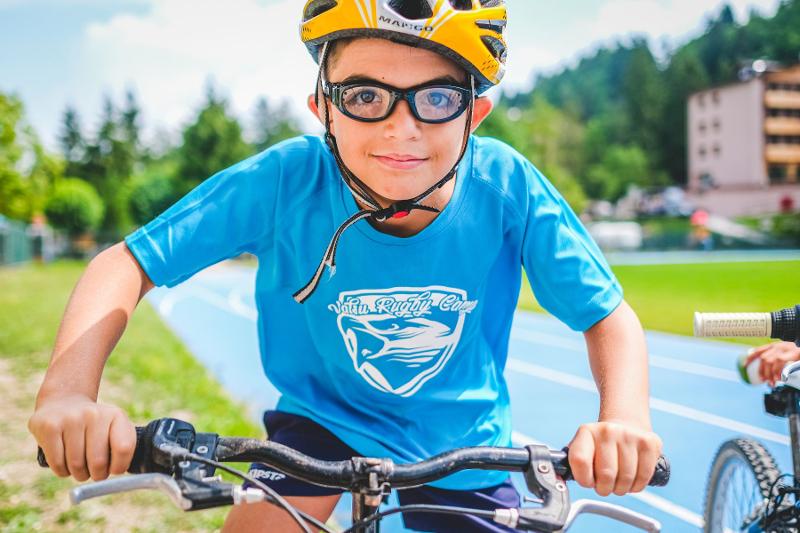 Un giovane partecipante del campo estivo multisport è in sella alla sua bicicletta