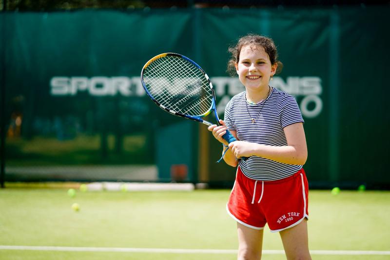 Una bambina gioca a tennis al campo estivo multisport