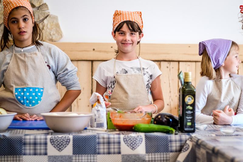 Al campo estivo cucina alcune bambine con delle bandane colorate in testa stanno per cucinare