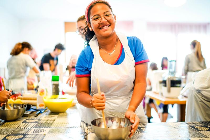 Una ragazza del campo estivo cucina mescola un impasto nella ciotola