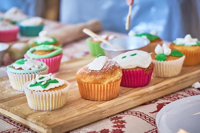 Al campo estivo cucina, i ragazzi cucinano e assaggiano dei muffin alla vaniglia con delle decorazioni verdi