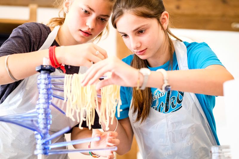 Due ragazze del campo estivo cucina stanno lavorando a mano della pasta fresca