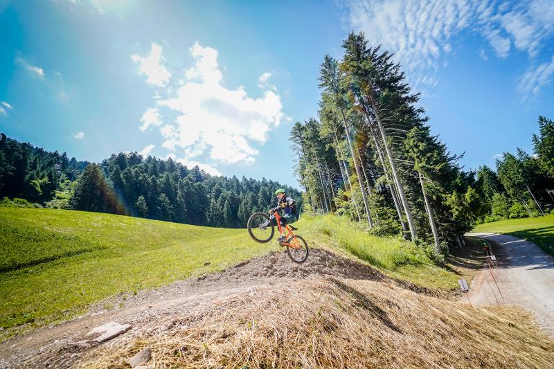Al campo estivo mountain bike un ragazzo esegue un salto sopra al prato in bici