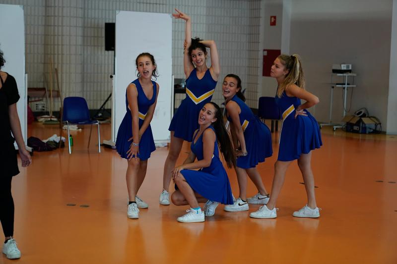 Al campo estivo recitazione cinque ragazze vestite da cheerleaders blu e gialle fanno una scenetta