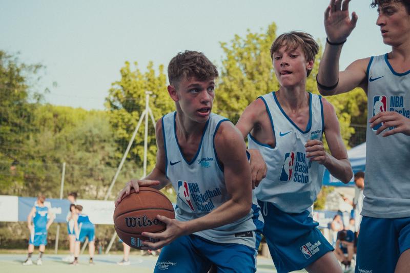 Tre partecipanti del campo estivo basket si contendono il pallone durante un azione
