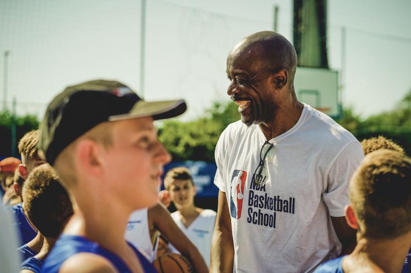 L'allenatore ride e scherza con i giovani giocatori del camp estivo basket