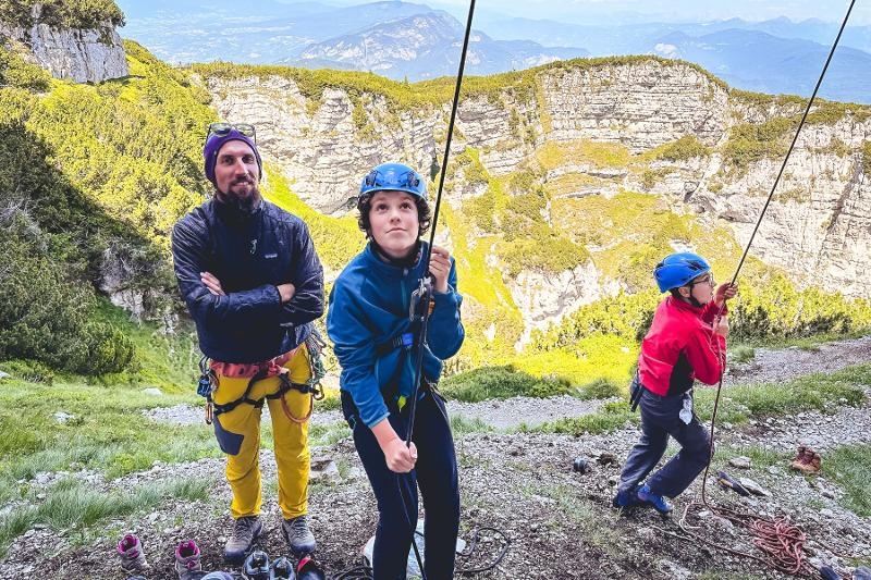 I partecipanti del campo estivo arrampicata fanno sicura ai loro compagni mentre gli insegnanti li osservano