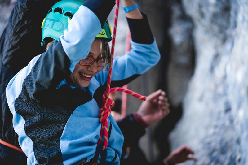 Una ragazza sorridente scende dalla parete su roccia al campo estivo arrampicata