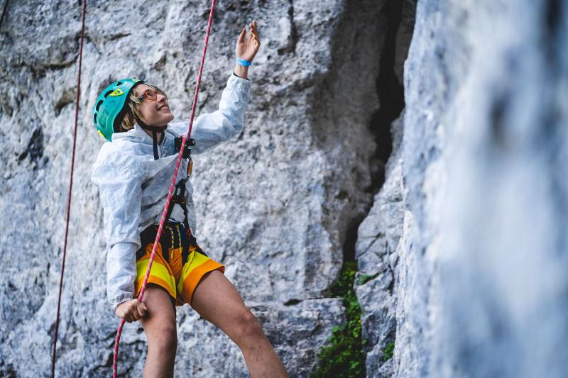 Una ragazza è sospesa in aria sorretta da una corda al campo estivo arrampicata
