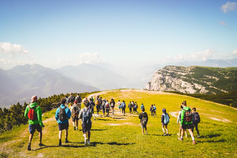 Al campo estivo Piemonte, i ragazzi stanno facendo una camminata in montagna in un prato verde con panorama