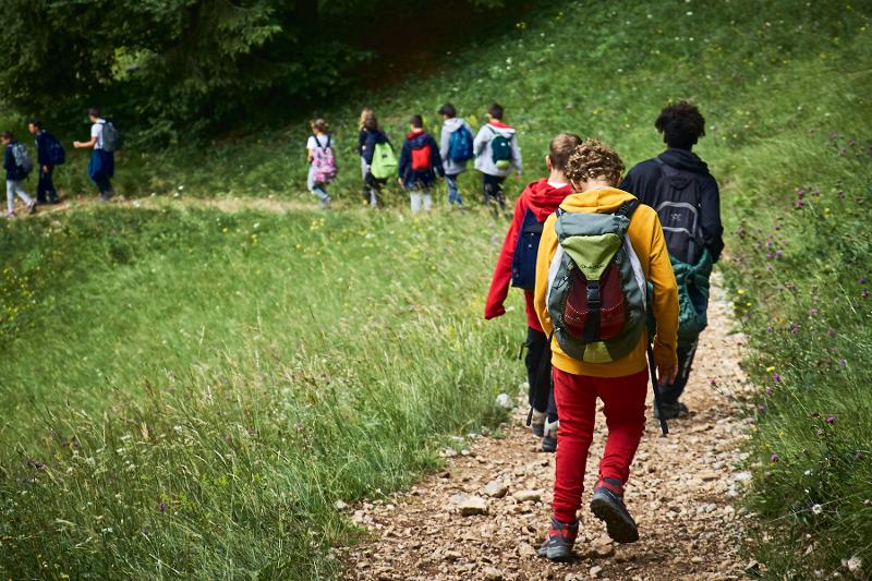 Al campo estivo Marche, tanti ragazzi stanno facendo un'escursione nella natura seguendo un percorso tracciato