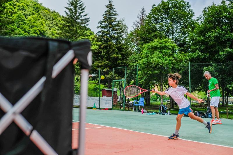 Un partecipante del campo estivo tennis e multisport colpisce la pallina con un dritto potente