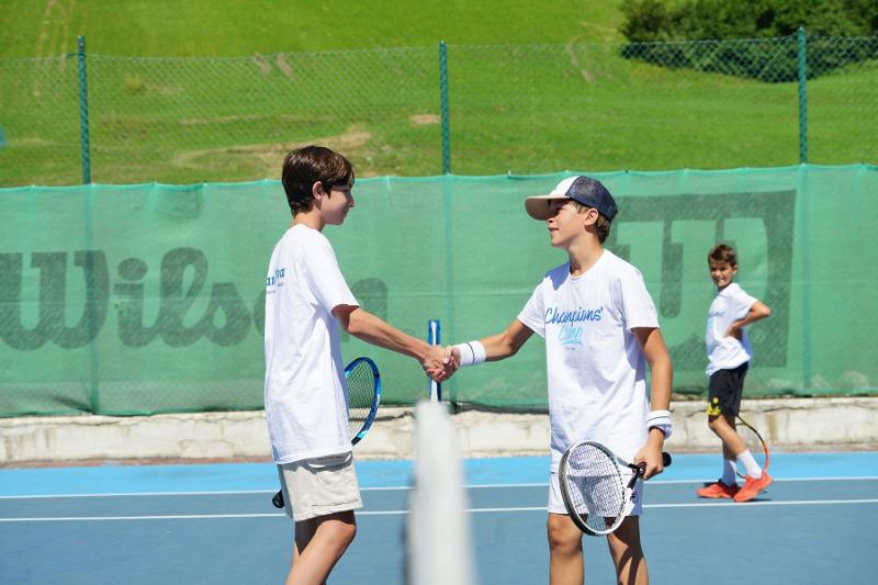 Due giovani atleti del campo estivo tennis e multisport si stringono la mano dopo la partita in segno di fairplay