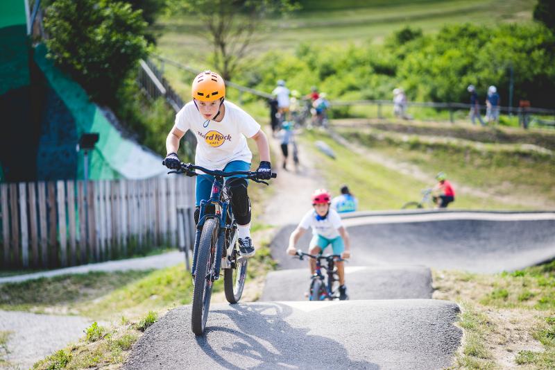Due ragazzi stanno facendo mountain bike su un percorso in strada in mezzo al verde al campo estivo tennis e multisport