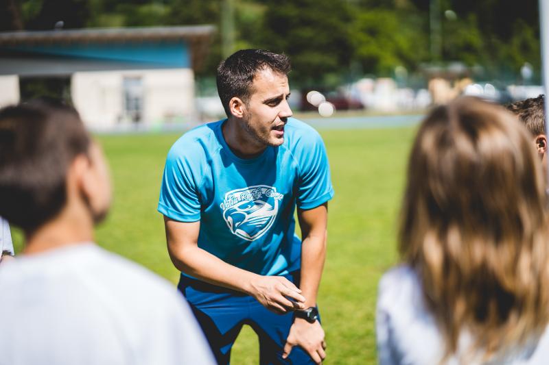 Al campo estivo rugby l'allenatore sta dando consigli ai ragazzi in campo
