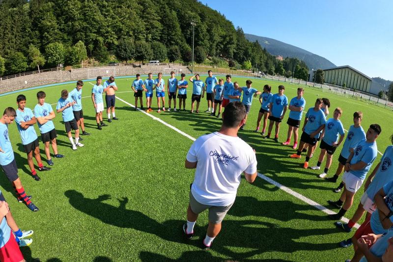 I giocatori del campo estivo rugby ascoltano l'allenatore in cerchio
