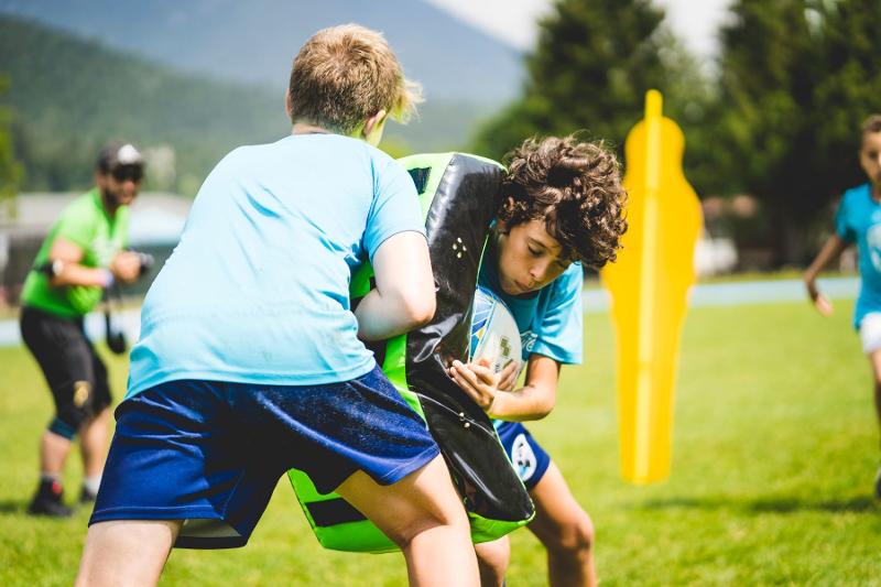 Due giocatori si allenano sui placcaggi e gli sfondamenti al campo estivo rugby