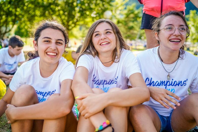 Ai campi estivi Friuli Venezia Giulia, tre ragazze sorridenti stanno insieme sul prato
