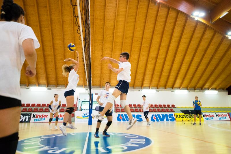 Al campo estivo pallavolo un ragazzo esegue una schiacciata e l'avversaria a rete prova a fare il muro per intercettare la palla