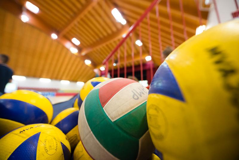 Ci sono vari palloni colorati di verde, bianco, rosso, giallo e blu al campo estivo pallavolo