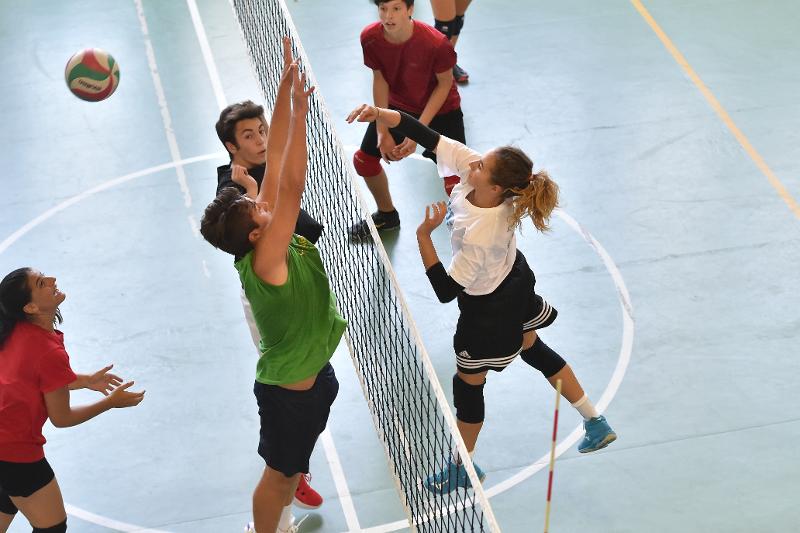 Al campo estivo pallavolo i ragazzi delle due squadre diverse a rete eseguono un contrasto in aria