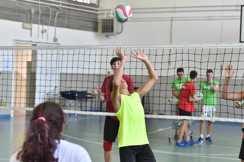 Un ragazzo esegue un palleggio sotto rete al campo estivo pallavolo
