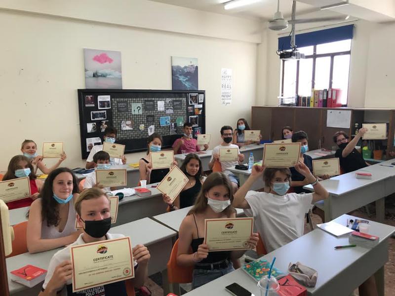 Al campo estivo internazionale a Cipro i ragazzi sono in aula che stanno mostrando il loro certificato di fine corso 