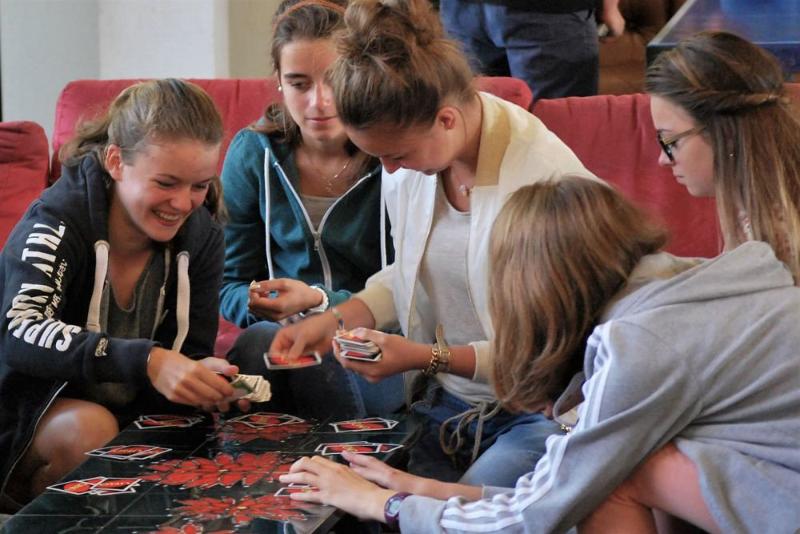 Alcune ragazze giocano a carte nei divanetti e sul tavolo al soggiorno linguistico Belgio